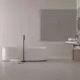 Freistehende Badewanne von Ideal Standard mit minimalistischer Form und einer schlanken Wandarmatur in mattschwarz. Handtücher liegen auf dem Boden. Helle, neutrale Farben dominieren den Raum.